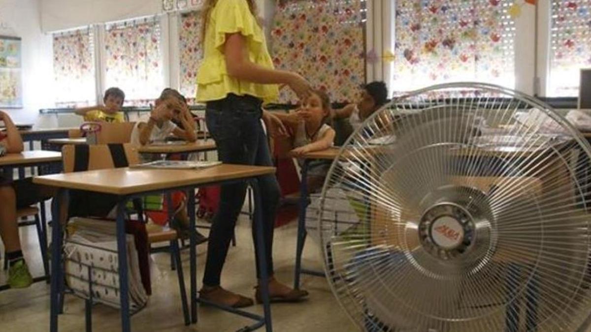 Niños en una aula con un ventilador para combatir el calor.