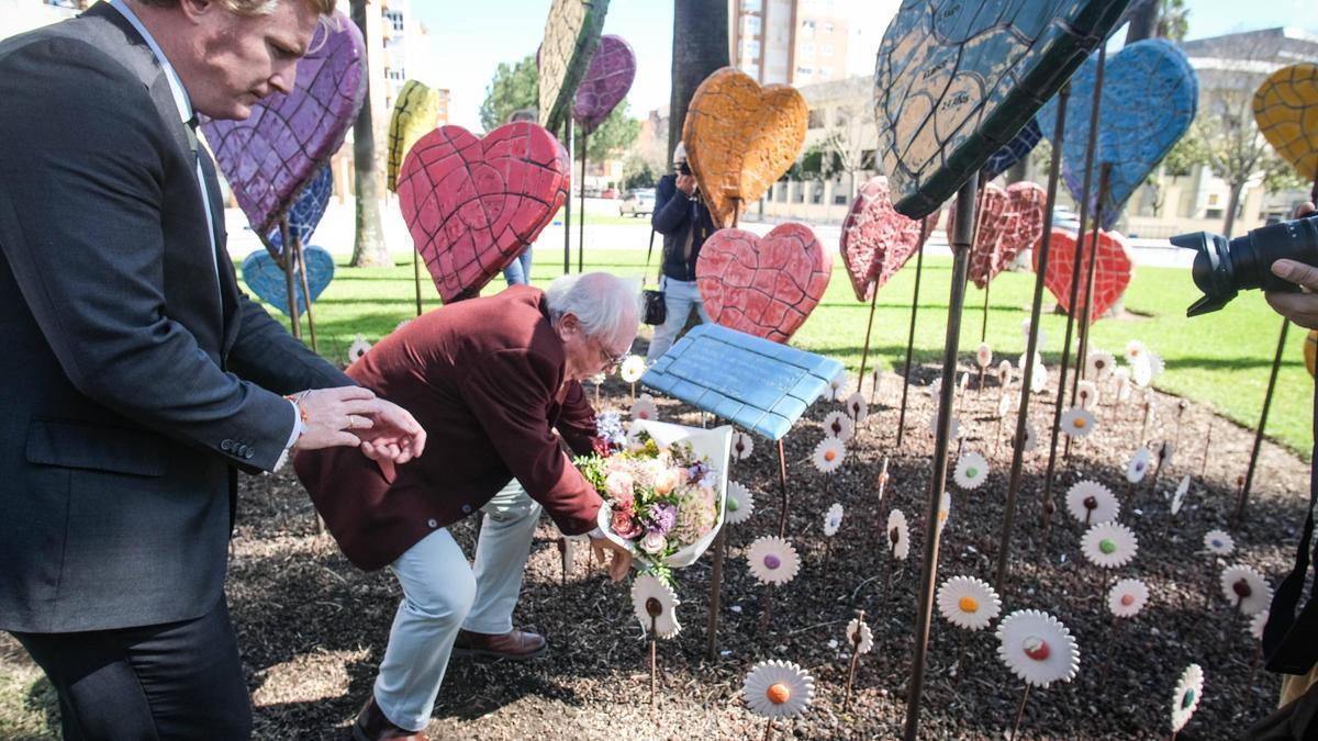 Antonio Guerra y el alcalde depositan un ramo de flores junto a los corazones.