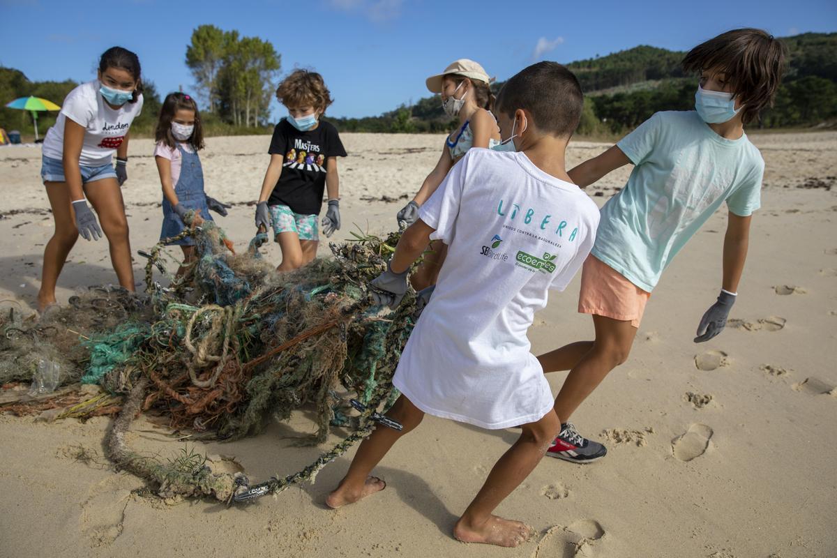 Varios niños retyiran baruraleza en la Praia de Limens (Pontevedra), en 2021.