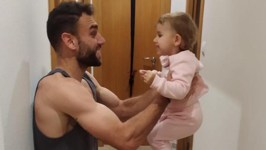 Gonzalo Verdú hace ejercicios en el pasillo de su casa junto a su hija.