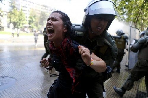 Un estudiante detenido por la policía durante una protesta contra una crisis financiera en la universidad de Chile