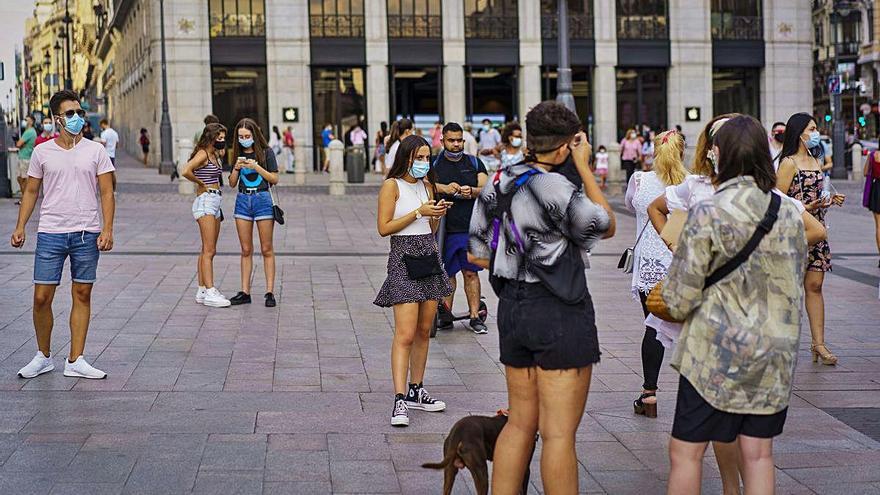 Varios jóvenes portando mascarillas en las calles de Madrid.