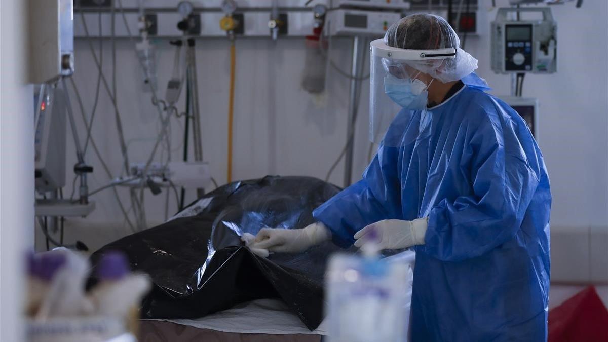 Un trabajador de un hospital de Buenos Aires limpia la bolsa que contiene una víctima mortal del covid-19, el pasado martes.