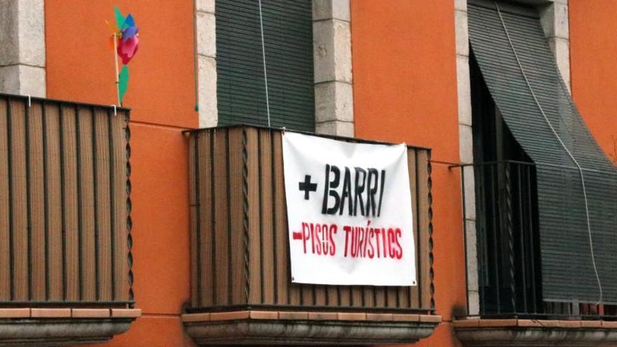 Una façana al Barri Vell de Girona amb una pancarta en contra dels pisos turístics.