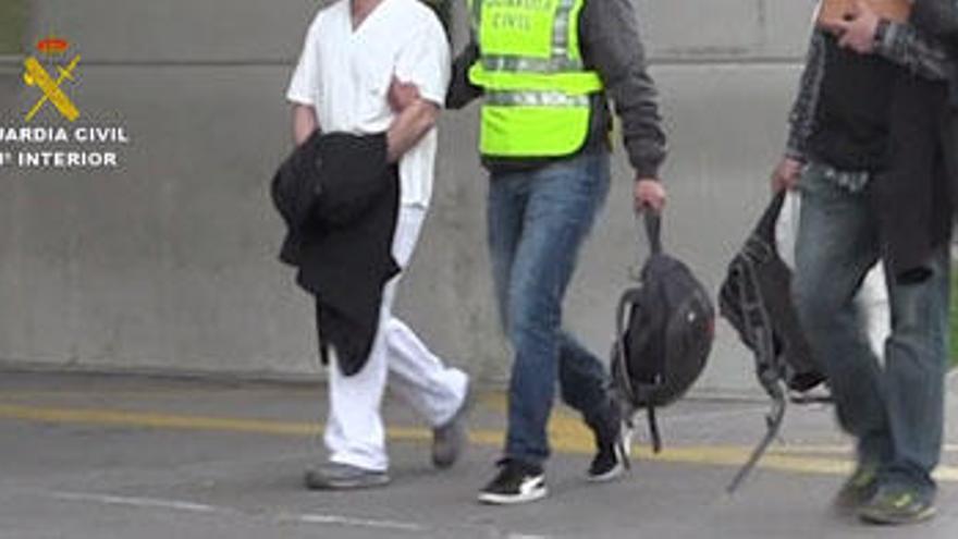 Dos agentes se llevan al falso médico detenido, tras arrestarlo en el Hospital de Figueres.