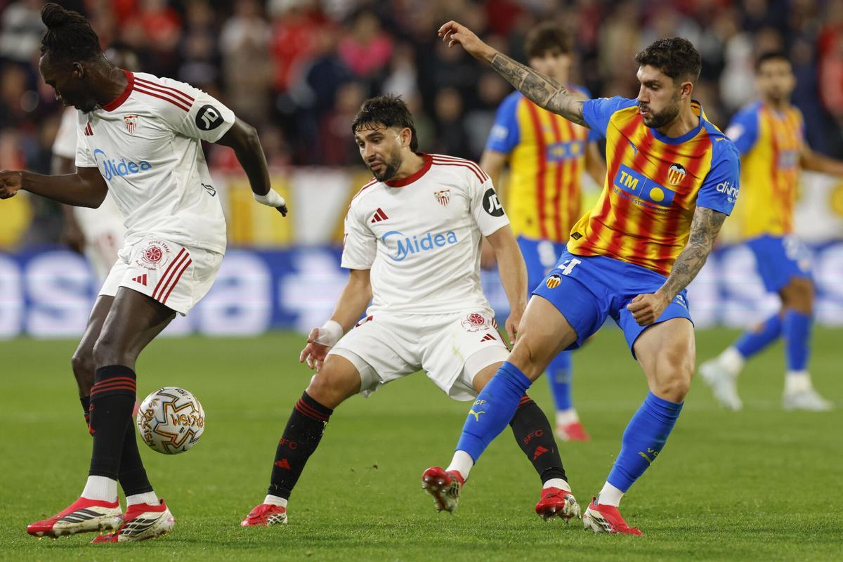 SEVILLA, 21/03/2026.- Los jugadores del Sevilla Batista Mendy (i) y Neal Maupay pelean un balón con Unai Núñez (d), del Valencia, durante el partido de LaLiga EA Sports que Sevilla FC y Valencia CF disputa, este sábado en el estadio Ramón Sánchez-Pizjuán. EFE/Julio Muñoz