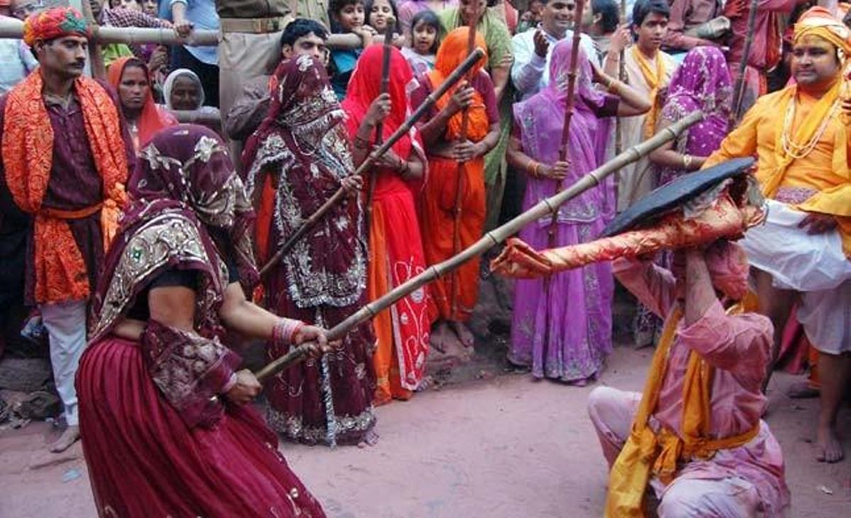 Un home es protegeix del cop que li clava una dona amb un pal de bambú durant les celebracions del Lathmar Holi, també conegudes com el festival dels colors, a Barsana (Índia).