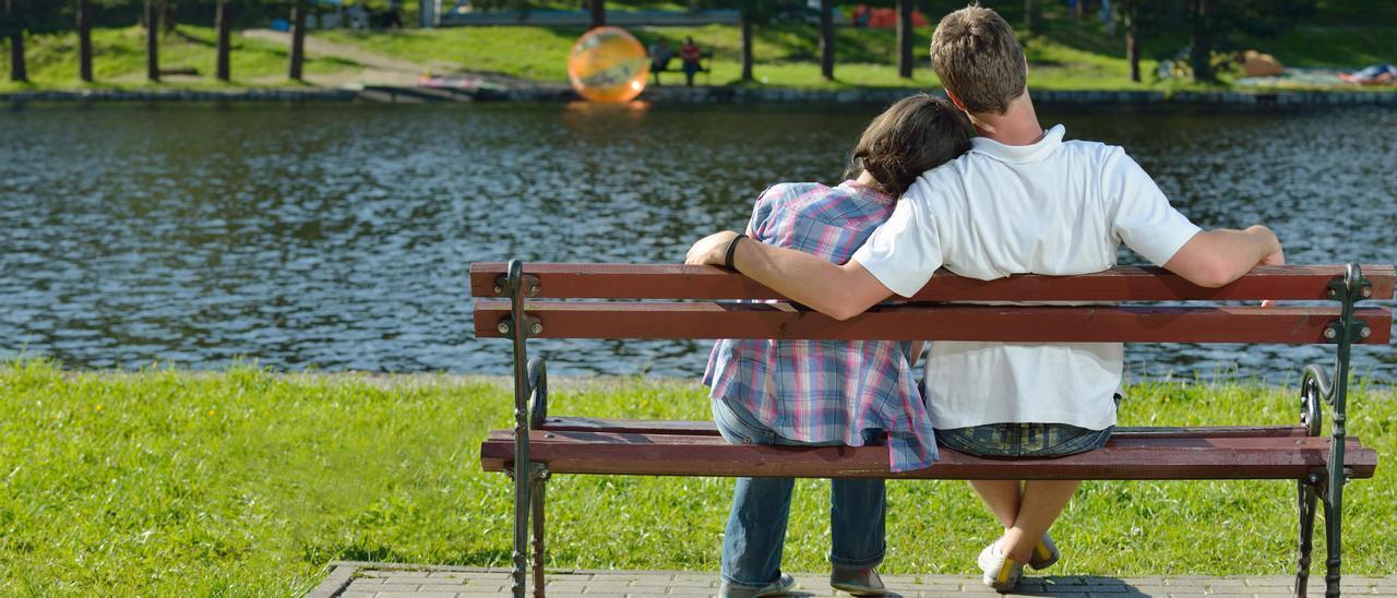 Una pareja de adolescentes, en el banco de un parque.