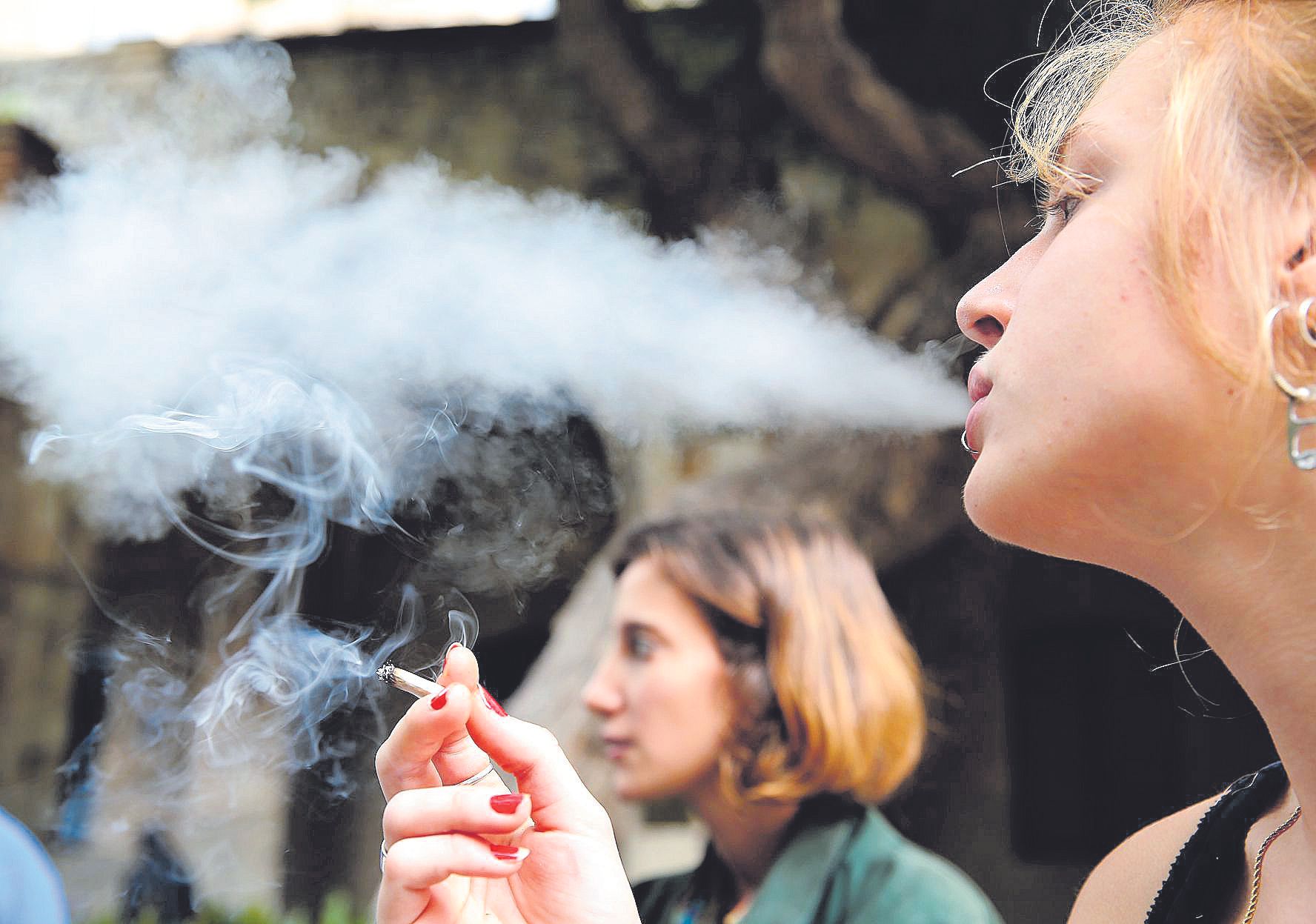 Dos jóvenes fuman un cigarrillo en una terraza