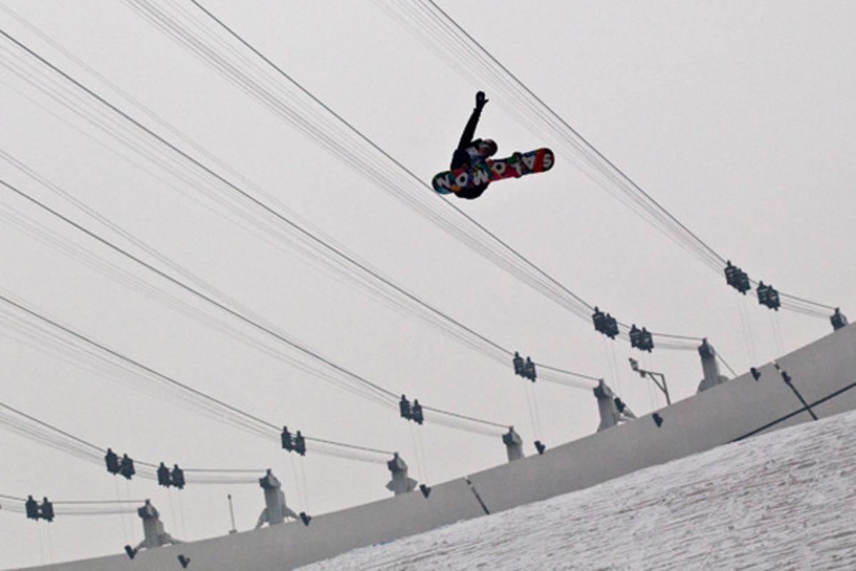 Un esportista de surf de neu practica el seu salt per a la competició Oakley Shaun White Air and Style a Pequín.