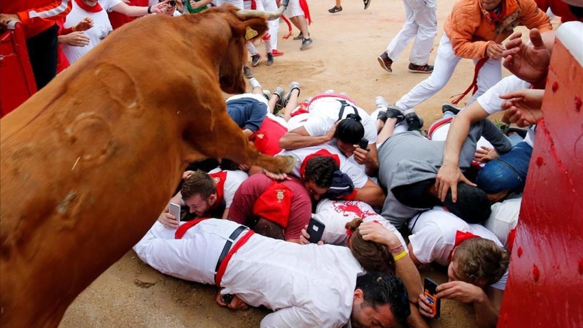 Un grupo de mozos grabando cómo les pasa una vaquilla por encima.