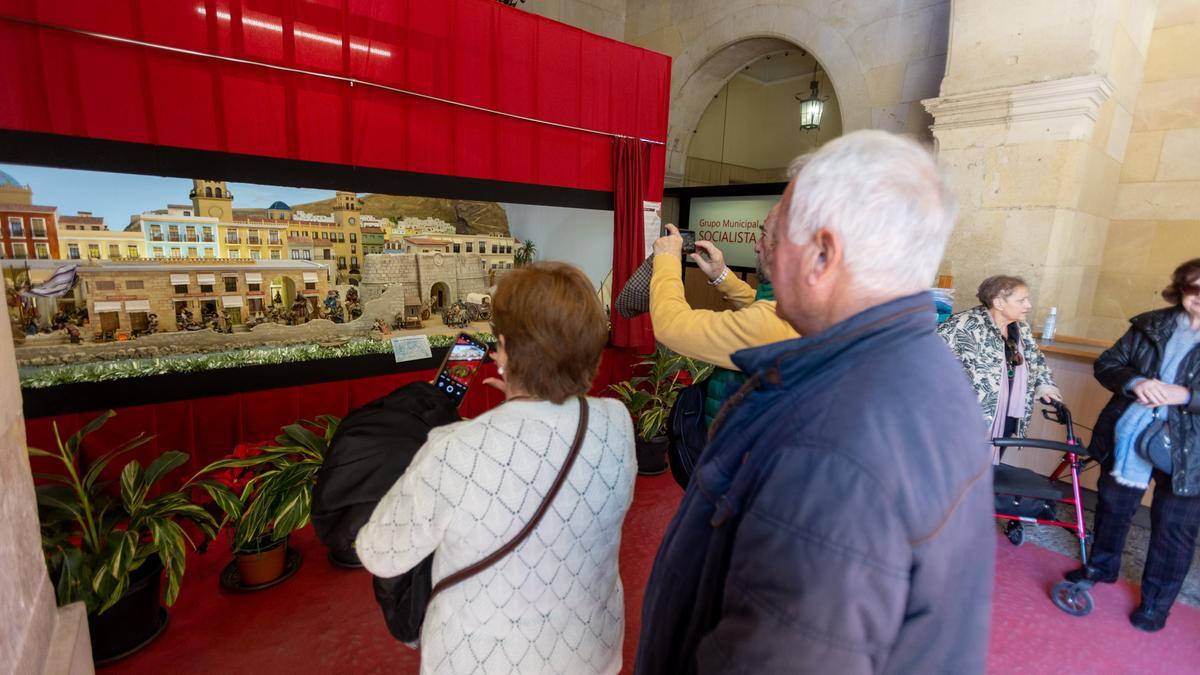 Tres personas realizan fotos al belén del Ayuntamiento de Alicante, esta semana.