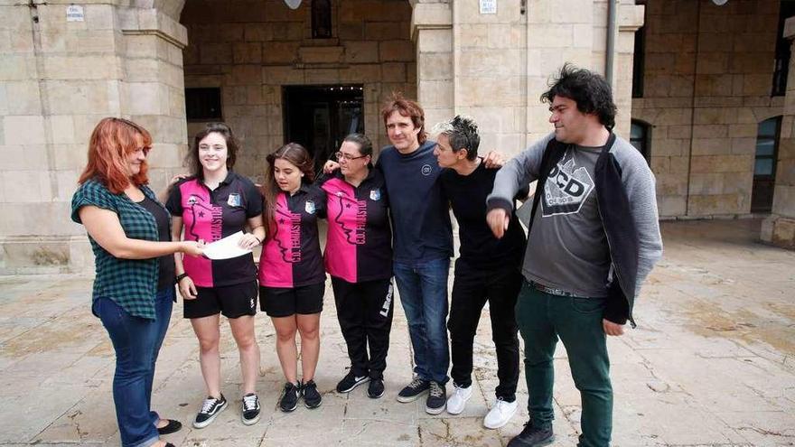 Los concejales de Somos Eva Fernández, Primitivo Abella y David Salcines, entregando un cheque a representantes del Femiastur ayer delante del Ayuntamiento.