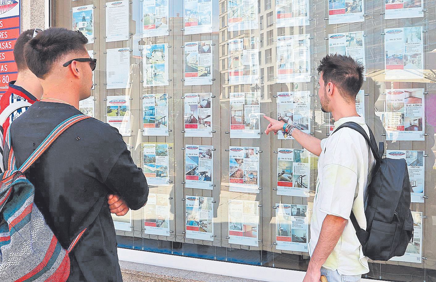 Jóvenes miran la oferta de pisos en una inmobiliaria