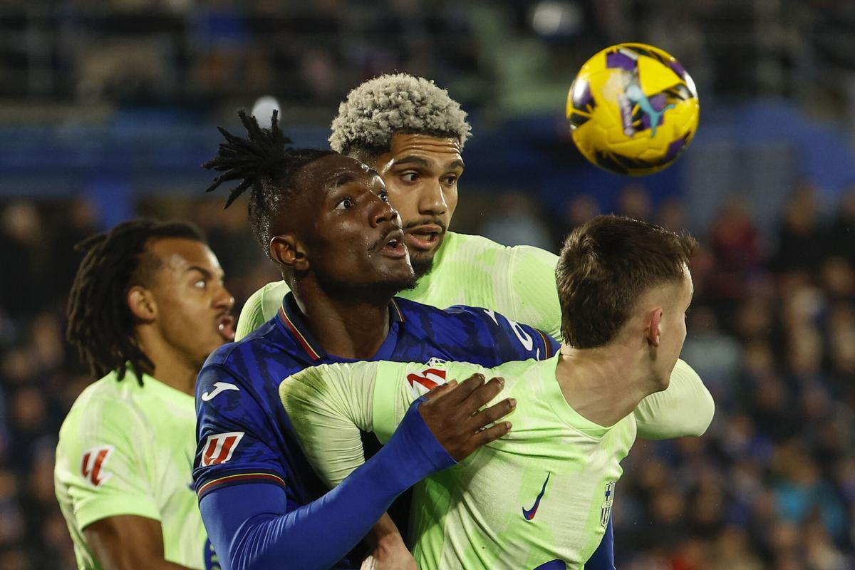 El centrocampista nigeriano del Getafe, Chrisantus Uche (c), disputa el balón ante los jugadores del FC Barcelona, el uruguayo Ronald Araujo y Marc Casadó (d), durante el encuentro correspondiente a la jornada 20 de Laliga EA Sports que disputan hoy sábado Getafe y FC Barcelona en el Coliseum de Getafe. EFE / Chema Moya.. (getafe) (Barcelona)