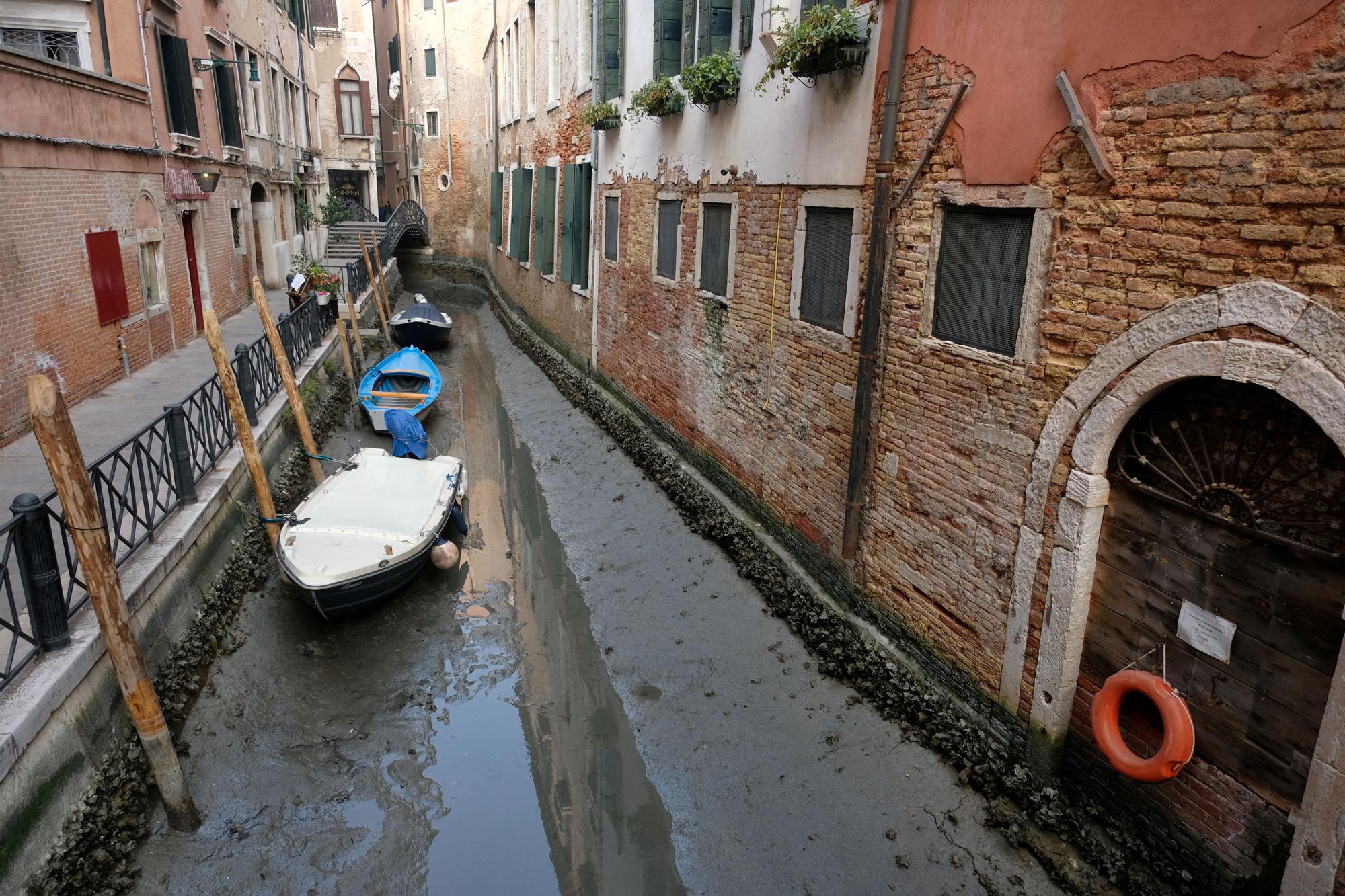 Boats are pictured in a canal during a severe low tide in the lagoon city of Venice