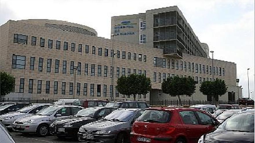 Vehículos aparcados ante la fachada del hospital de la Ribera ubicado en Alzira.