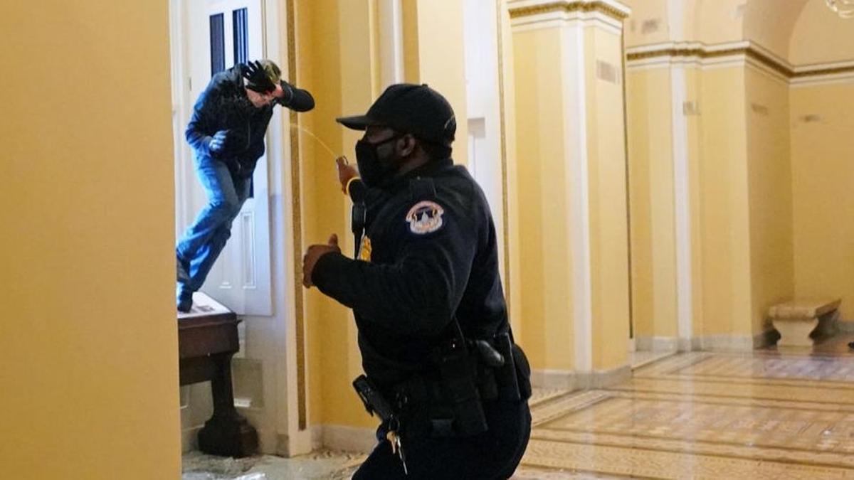 Un agente de policía le echa espray pimienta a uno de los manifestantes que se ha colado en el Capitolio.