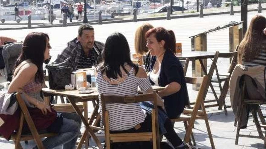 Clientes en una terraza con vistas al puerto deportivo.