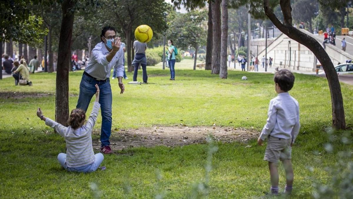 Unos niños juegan con su padre en un parque de Valencia, tras más de un mes encerrados por el coronavirus