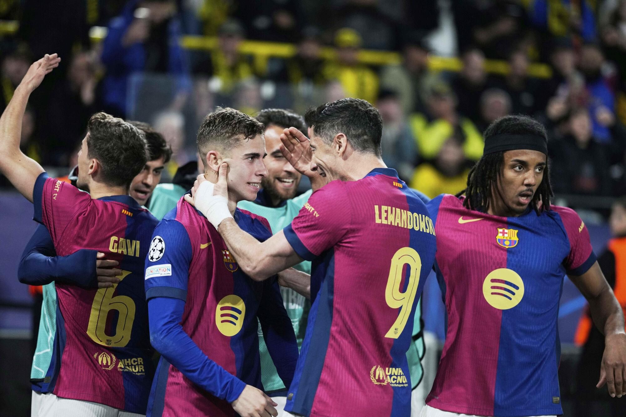Barcelona's Robert Lewandowski (9) and Fermin Lopez celebrate after forcing an own goal by Dortmund's Ramy Bensebaini during the Champions League quarterfinals second leg soccer match between Borussia Dortmund and Barcelona, at the Signa-Iduna Park in Dortmund, Germany, Tuesday, April 15, 2025. (AP Photo/Matthias Schrader). EDITORIAL USE ONLY/ONLY ITALY AND SPAIN