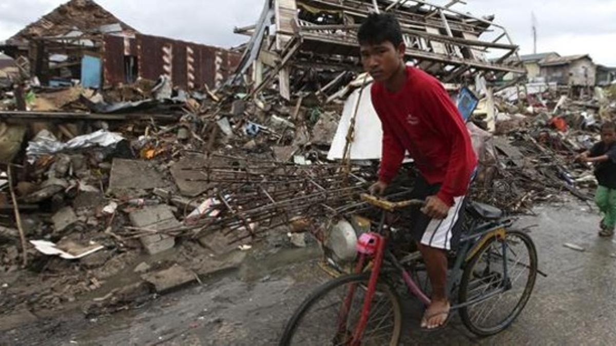 Un afectado por el tifón 'Hayan' monta en bicicleta en la devastada ciudad de Tacloban, este jueves.