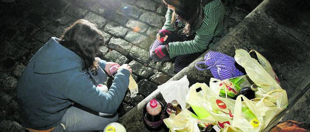 Dos jóvenes se sirven bebidas alcohólicas en un botellón.