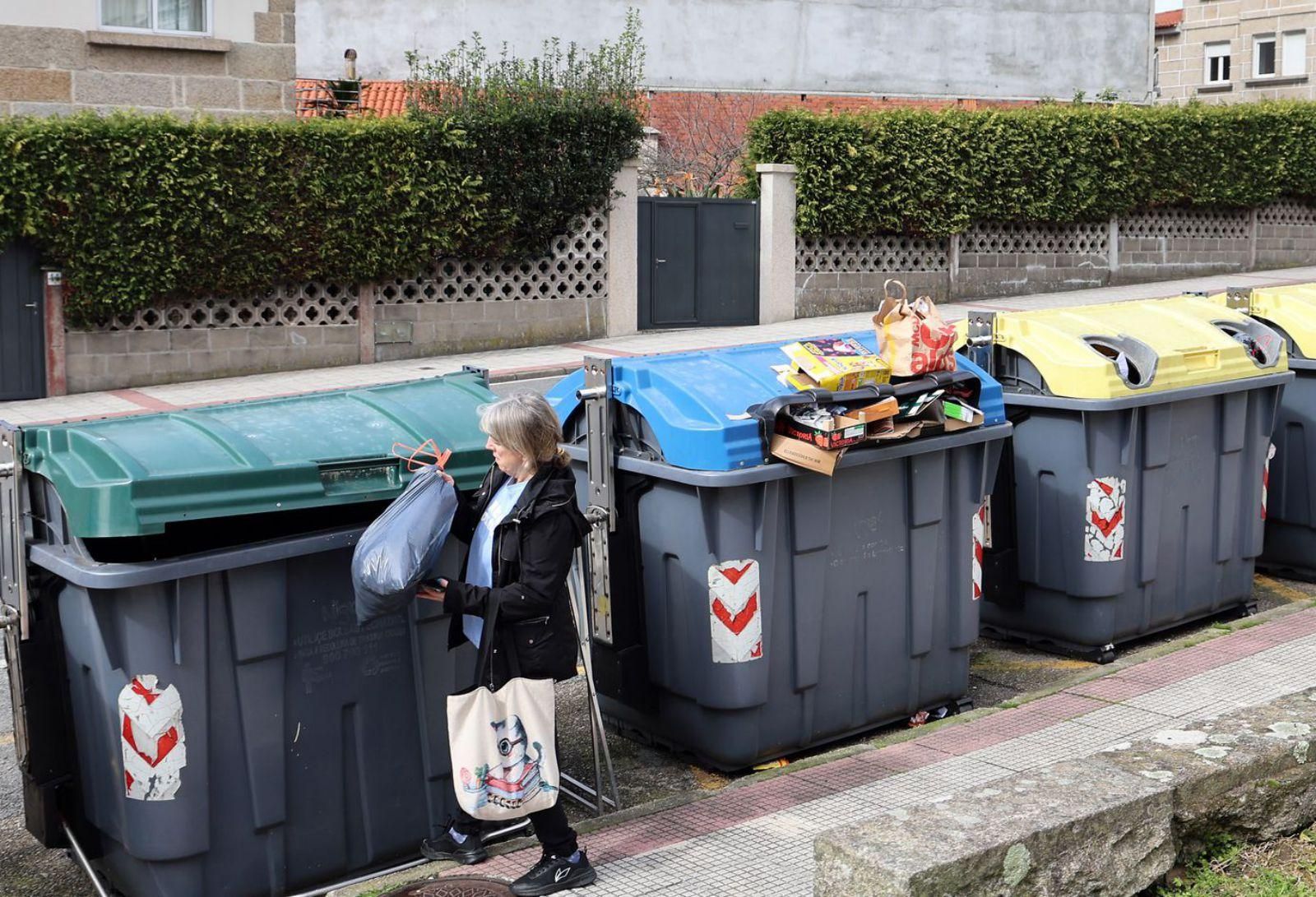 Una mujer deposita la basura en un contenedor