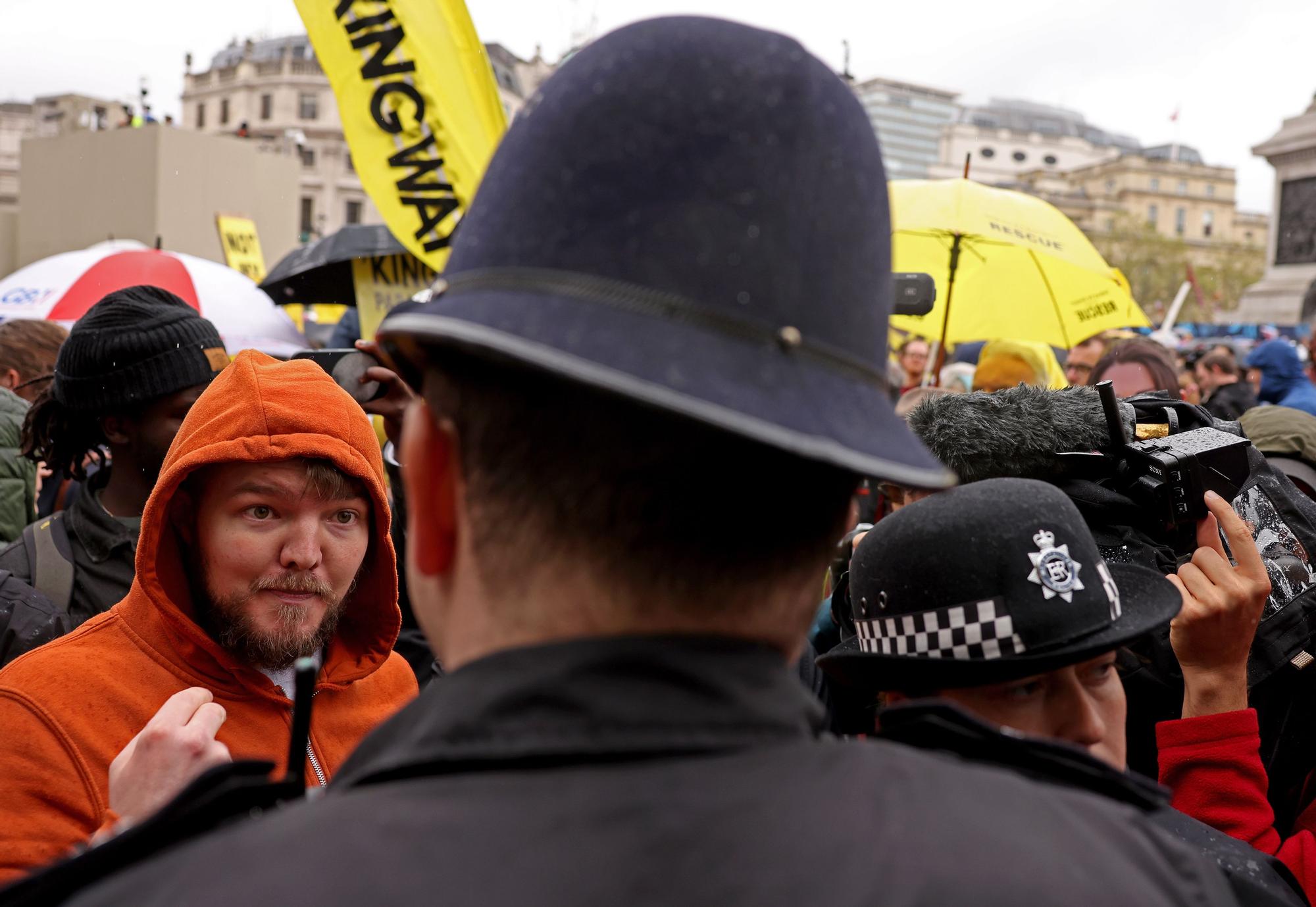 Un hombre habla con un policía durante la protesta de antimonárquicos en el día de la coronación de Carlos III.