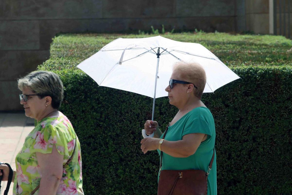MLG 07-08-2025.-Varias personas se refrescan con abanicos en la segunda ola de calor que azota a la península