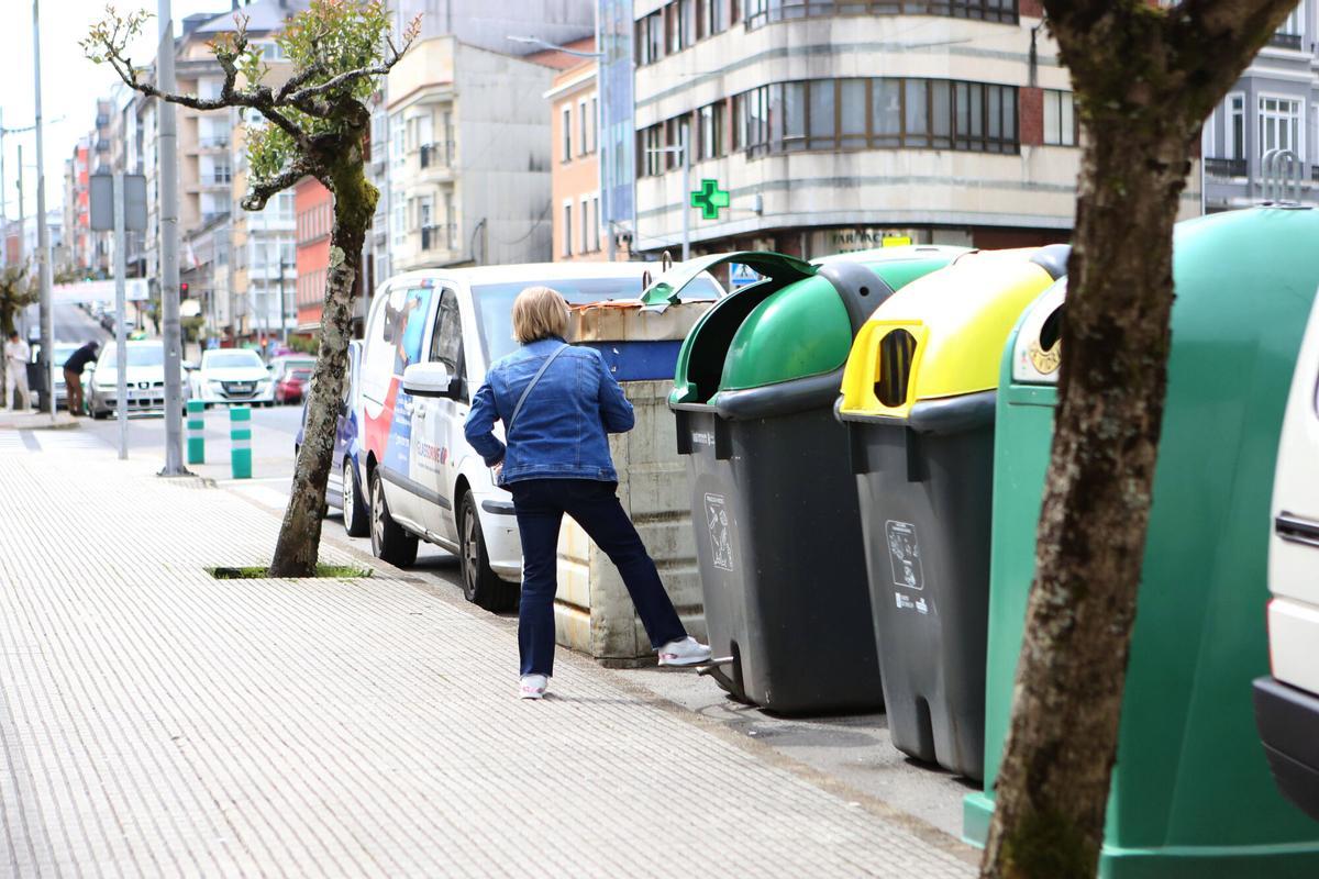 Una estradense tira la basura en un contenedor de la avenida Benito Vigo.