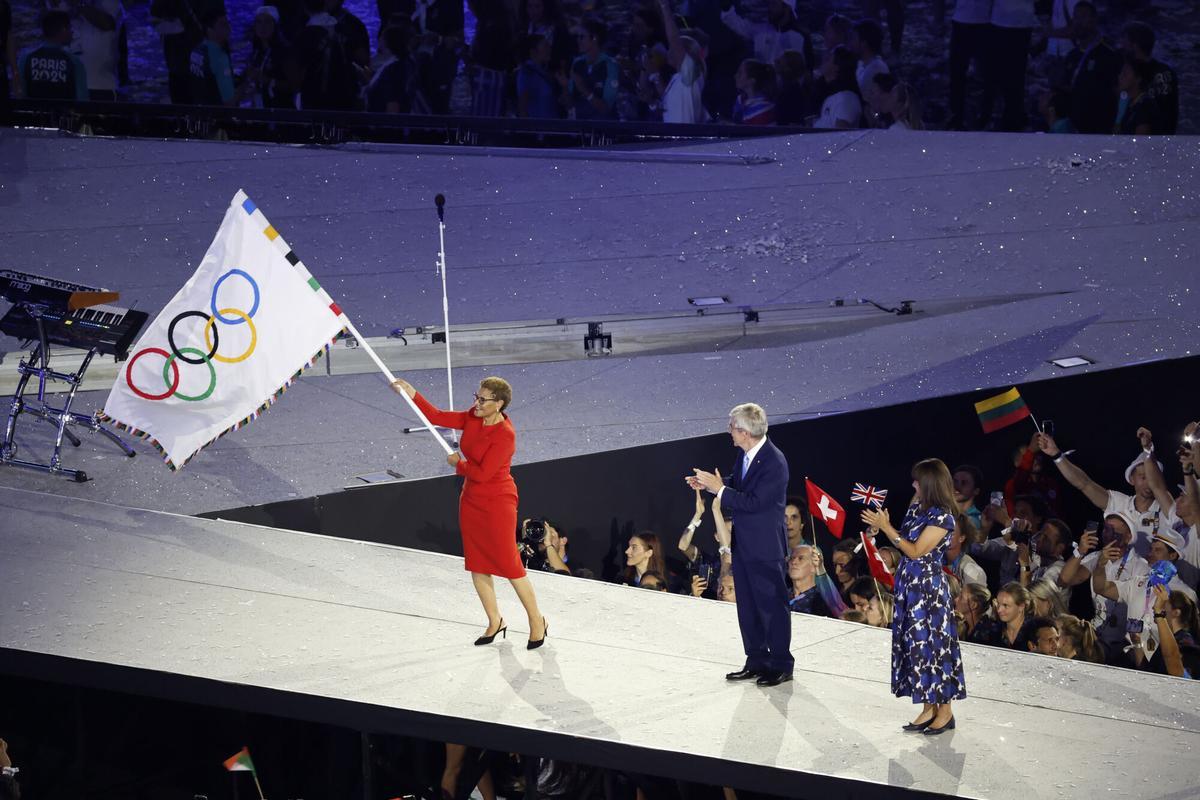 La alcaldesa demócrata de Los Angeles, Karen Bass, ondea la bandera olímpica, junto al presidente del COI, Thomas Bach, durante la ceremonia de clausura de los Juegos Olímpicos de París 2024.