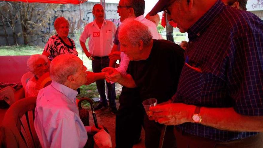 A la izquierda, Cayo Lara charla con los asistentes a la fiesta de IU. A la derecha, estatuillas a la venta de los grandes líderes comunistas, de Marx a Stalin o Hugo Chávez.