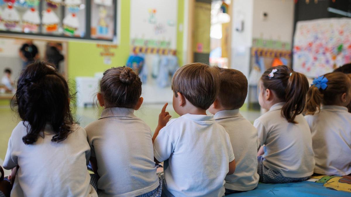 Niños y niñas de espaldas en una guardería infantil.