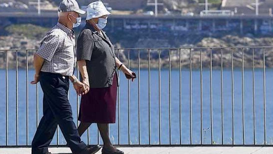 Una pareja, con mascarillas, camina por el paseo marítimo de A Coruña. | Carlos Pardellas