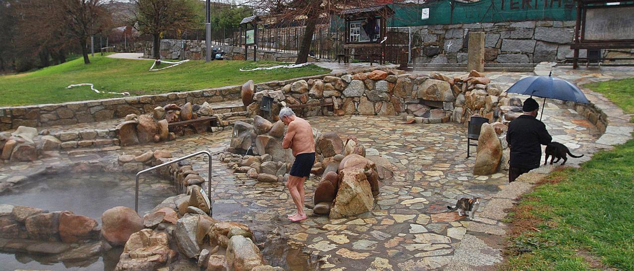 Bañistas, ayer, retando al frío y la lluvia, en AChvasqueira. Al fondo, uno de los bancos cuya madera ha sido expoliada. |   // IÑAKI OSORIO