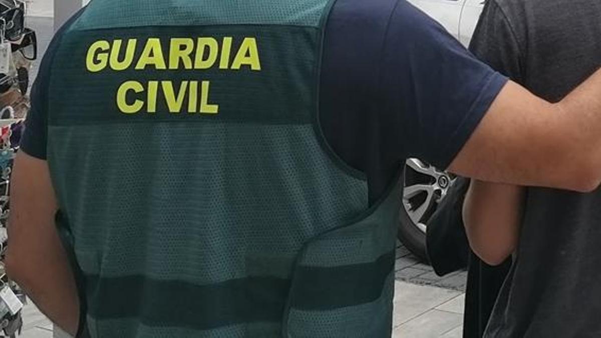 Un guardia civil lleva detenido a uno de los presuntos ladrones de dinero en restaurantes.