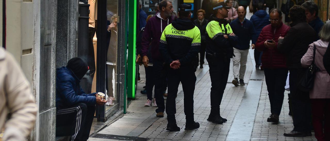 Policía Local de Plasencia y una persona pidiendo en la calle.