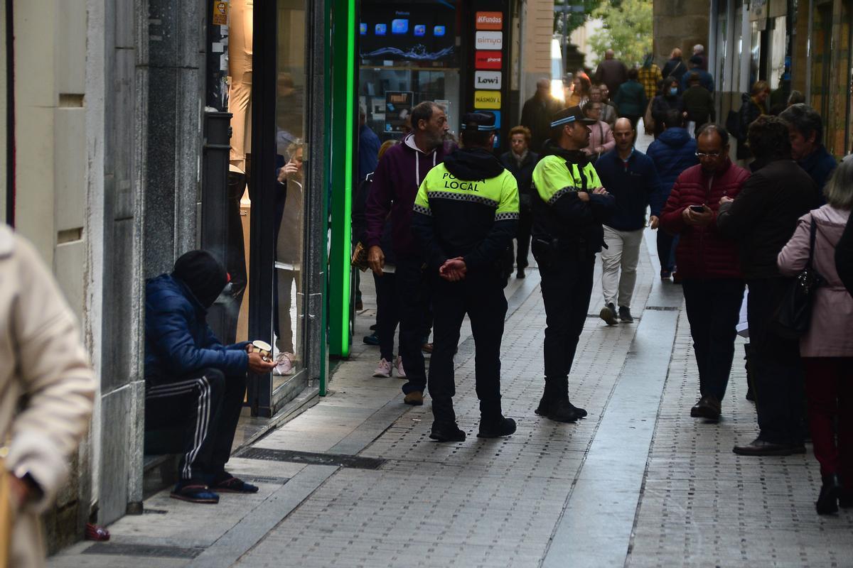 Policía Local de Plasencia y una persona pidiendo en la calle.