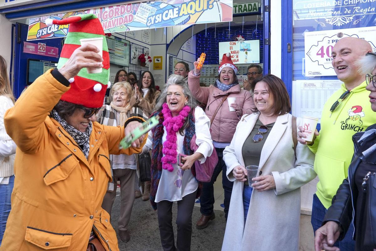 CHIPIONA (CÁDIZ), 22/12/2024.- Premiados y vecinos celebran este domingo el segundo premio del sorteo extraordinario de la lotería de Navidad caído en la administración número 1 de Chipiona (Cádiz). EFE/Román Ríos