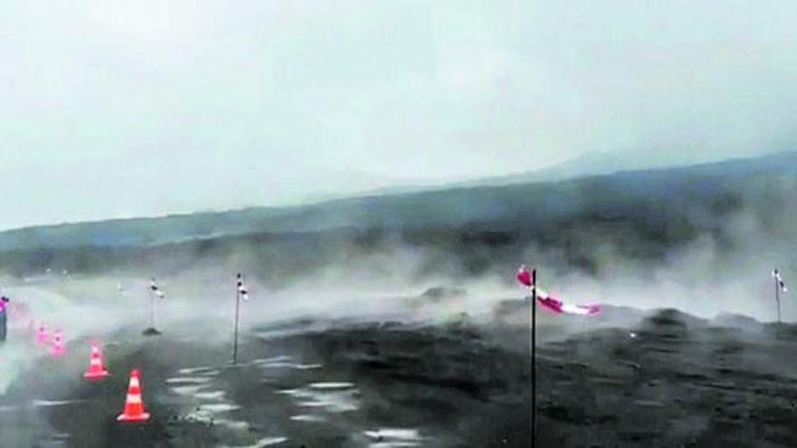 Varios vehículos transitan, entre nubes de vapor, por una carretera afectada por la erupción del volcán de Tajogaite.