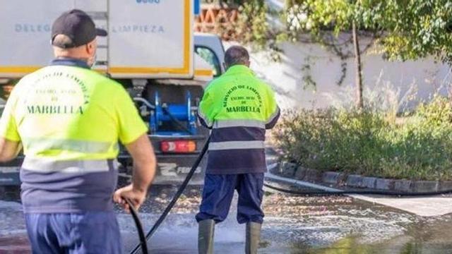 Dos operarios de limpieza baldean una calle de Marbella el pasado verano.