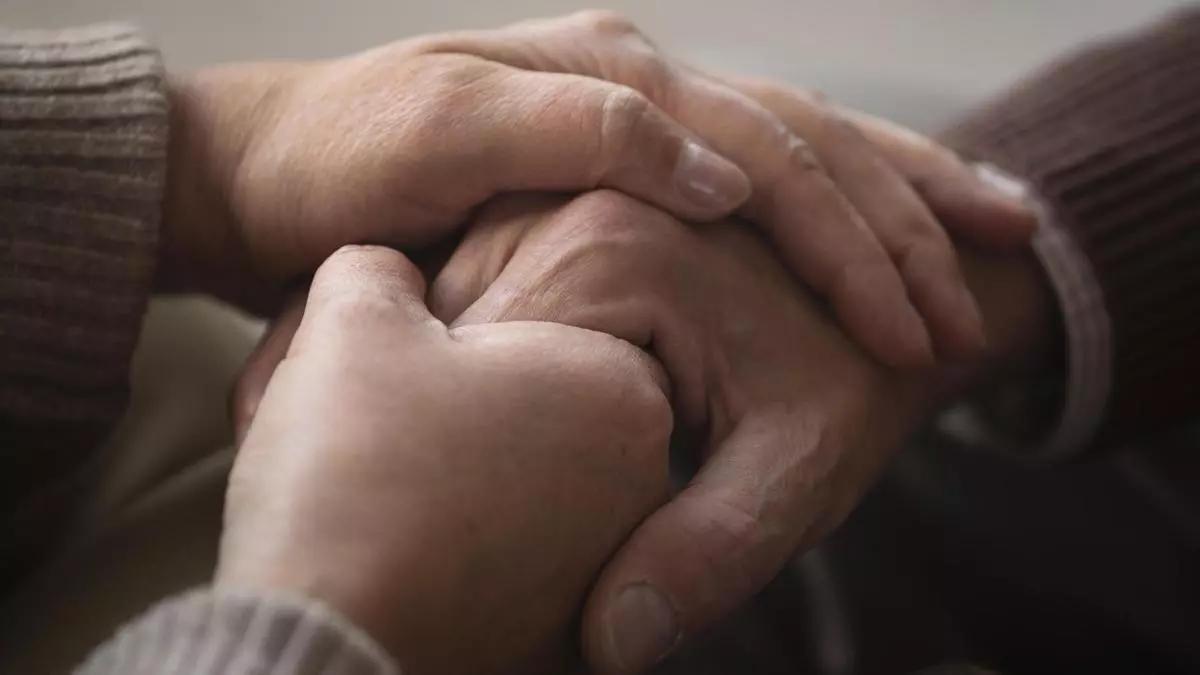 Un joven toma las manos de su padre.