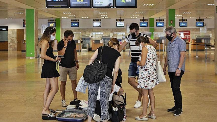 Un grup de turistes, a punt de facturar en un aeroport mig buit