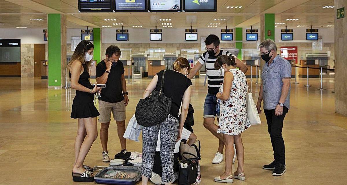 Un grup de turistes, a punt de facturar en un aeroport mig buit