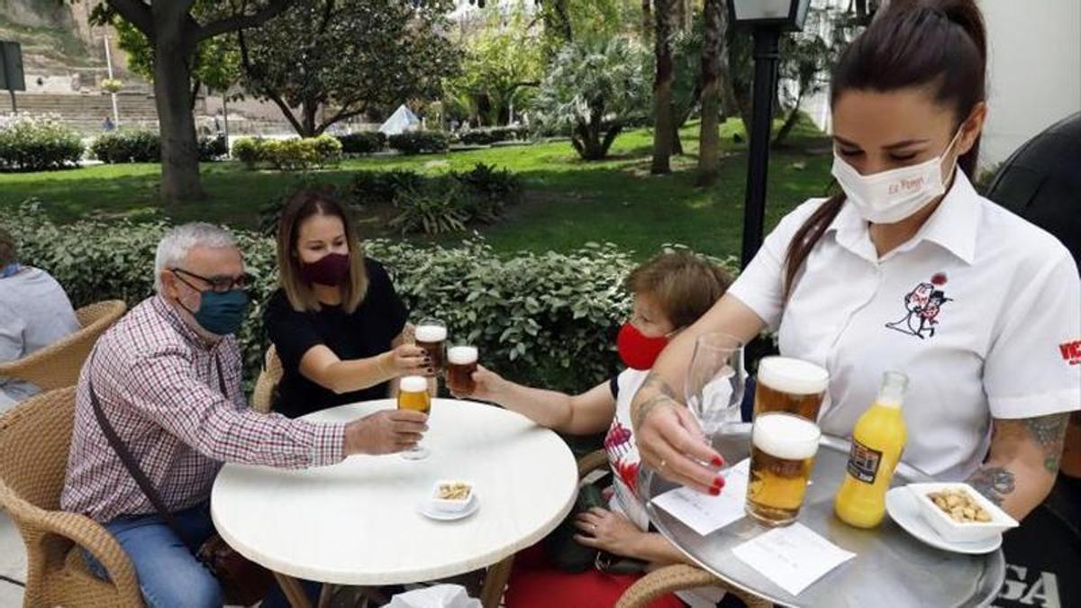 Una camarera sirve una comanda en un bar de la capital.