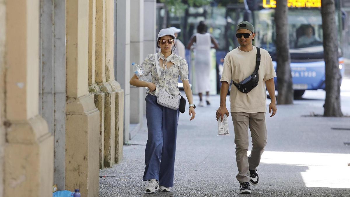 Turistes passejant amb aigua i gorra per la calor