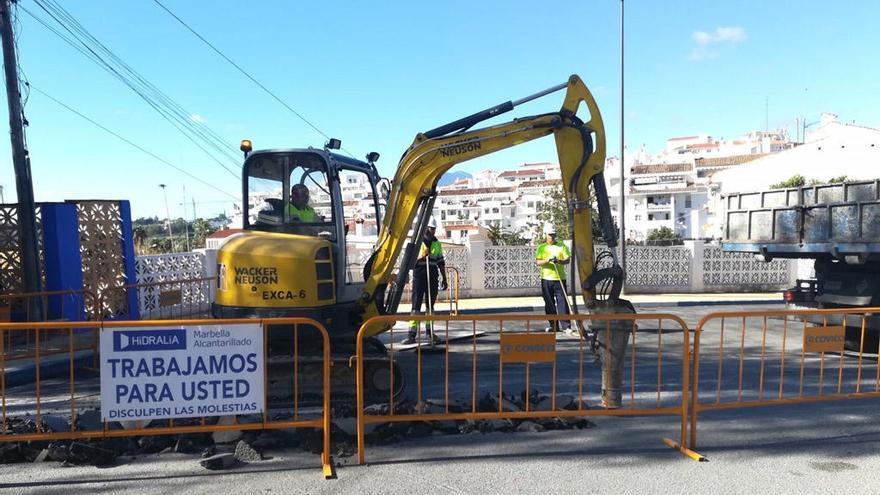 Operarios levantan la calzada con una grúa para mejorar el saneamiento de la calle.