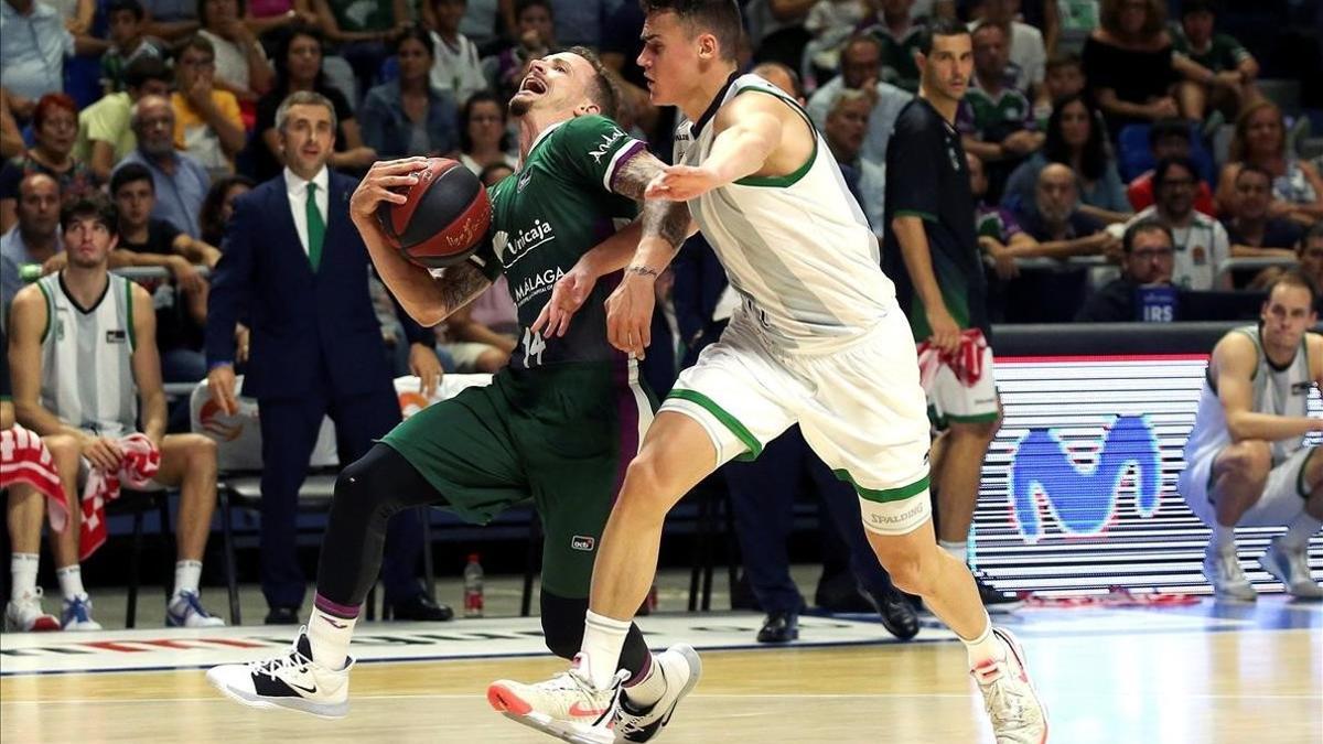 El base del Unicaja, Adams, pugna con el de la Penya, Dimitrijevic, por el control de un balón