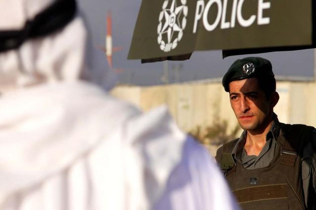 Un policia de fronteres israelià observa un grup de palestins en un dels controls de Kalandia.